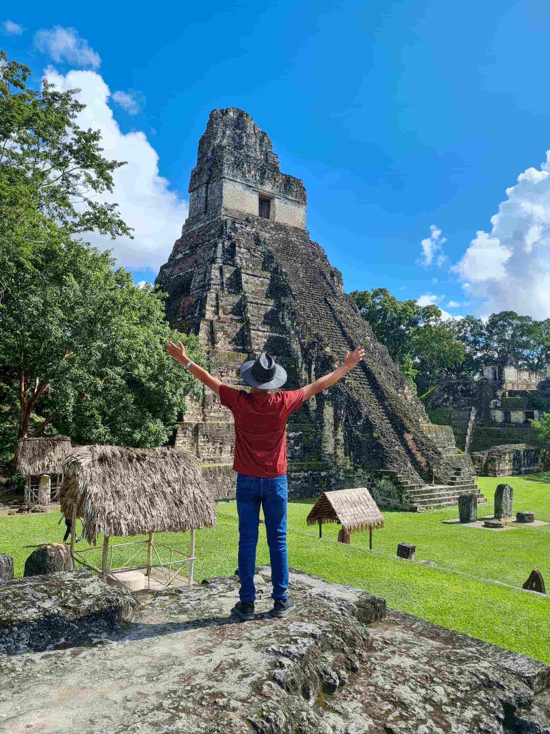 men with arms raised viewing the Temple I at Tikal against a blue sky (1)
